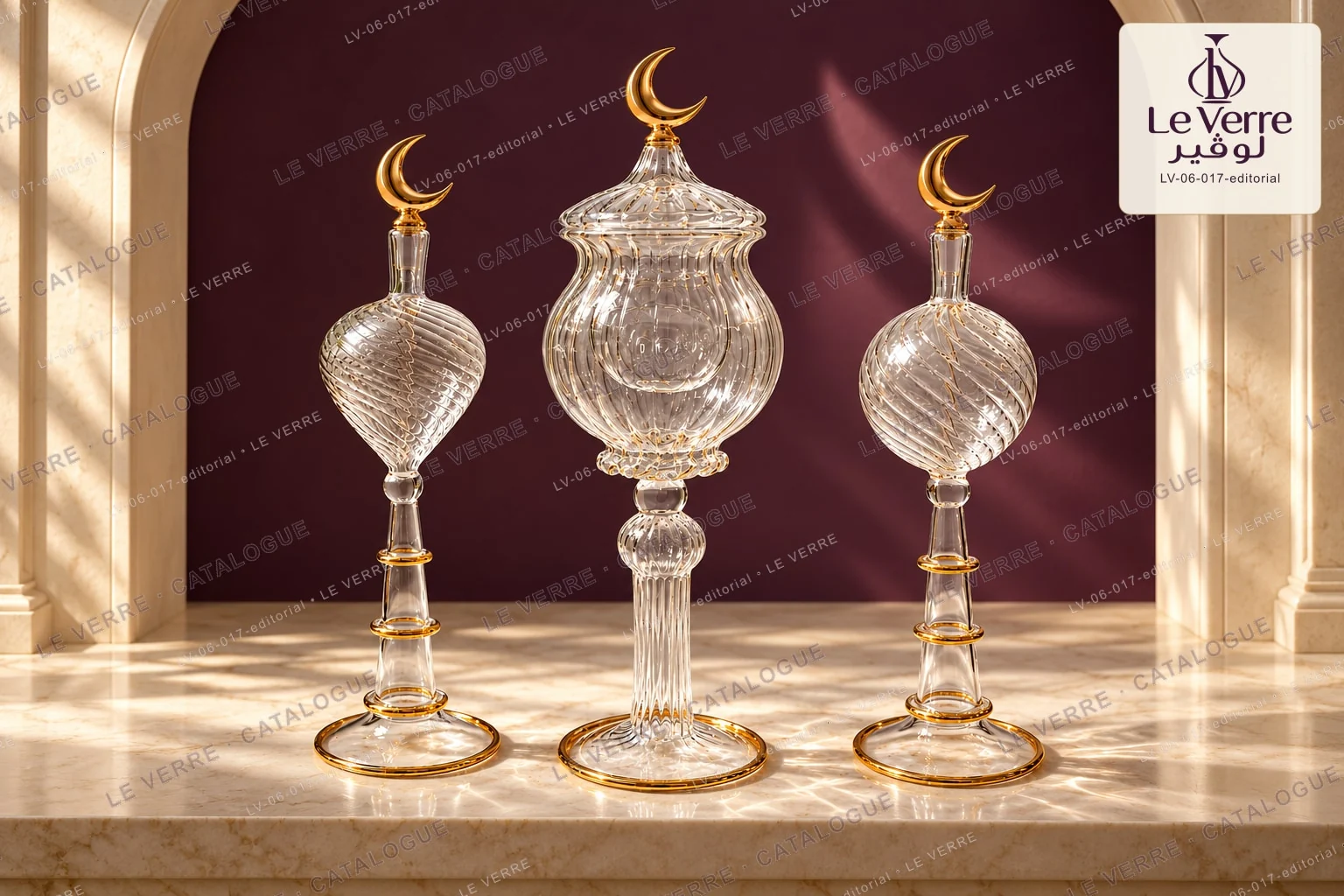 Three clear swirled glass pieces with gold-tone bands and crescent finials, including a lidded pedestal form, in a studio setting with arches